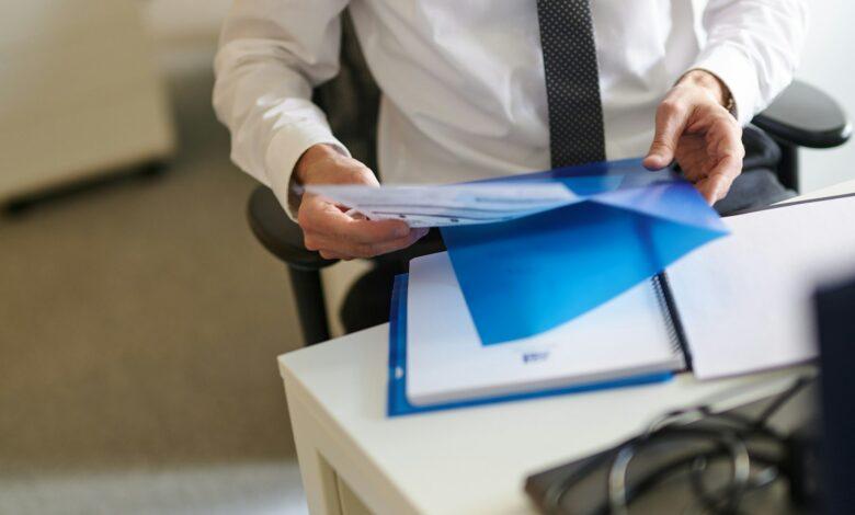 a man in a white shirt and tie holding a folder