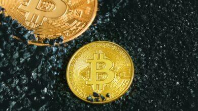two gold bitcoins sitting on a black surface