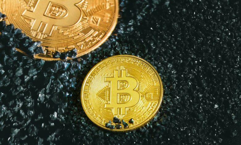two gold bitcoins sitting on a black surface