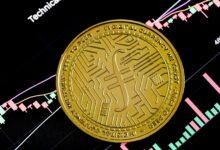 a gold coin sitting on top of a stock chart
