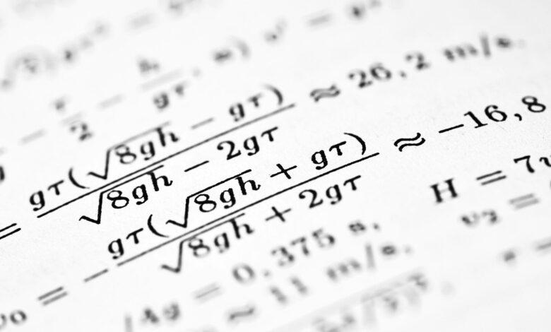 Mathematical formulas are written on a white sheet of paper.