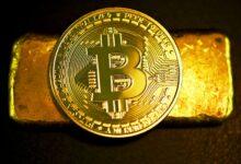a bitcoin sitting on top of a gold bar